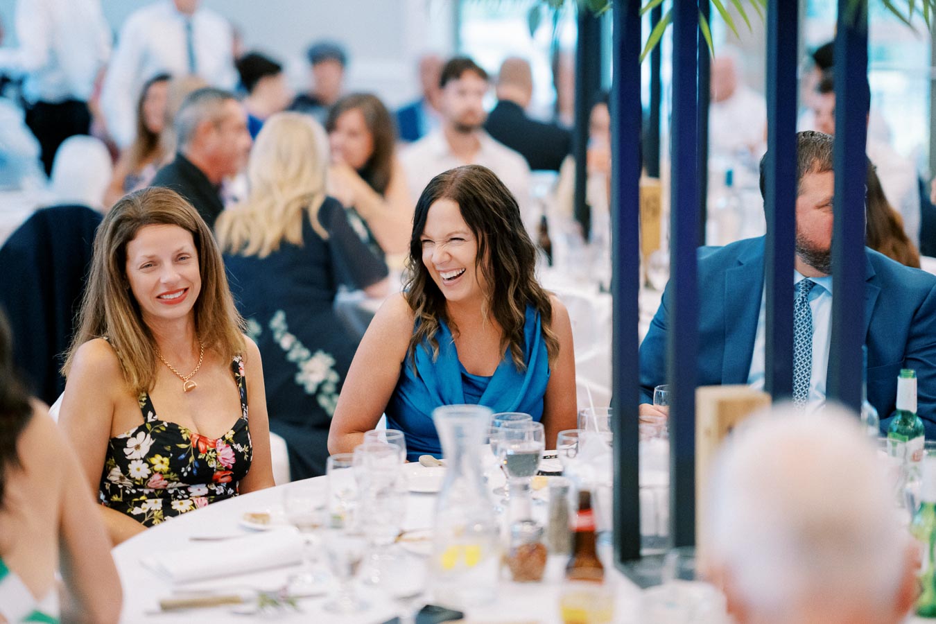 Group of people enjoying a lively conversation at a banquet table during an event, featuring elegantly dressed individuals and a festive atmosphere.