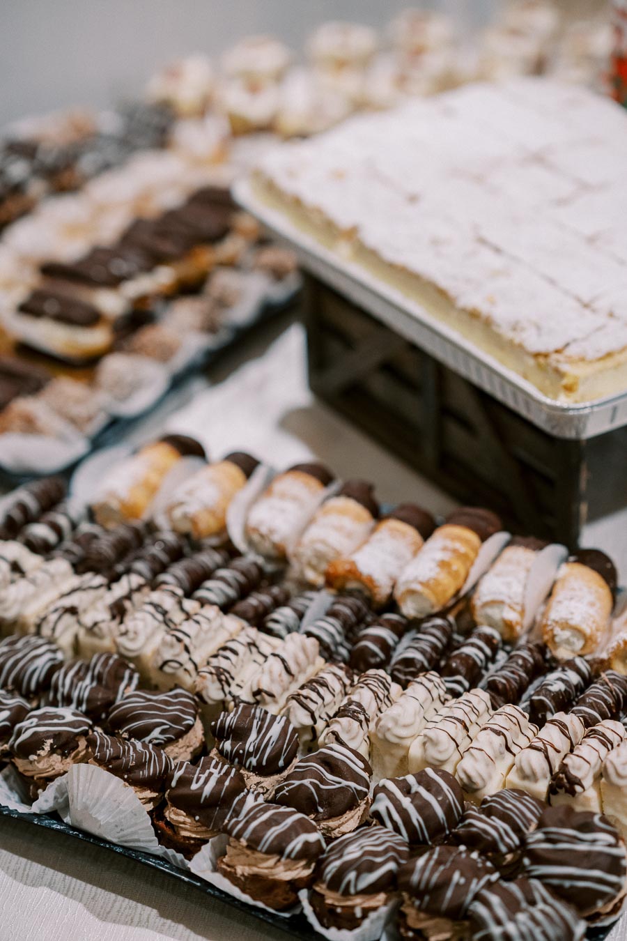 An assortment of delicious pastries including chocolate-covered eclairs and cream-filled desserts arranged on trays.