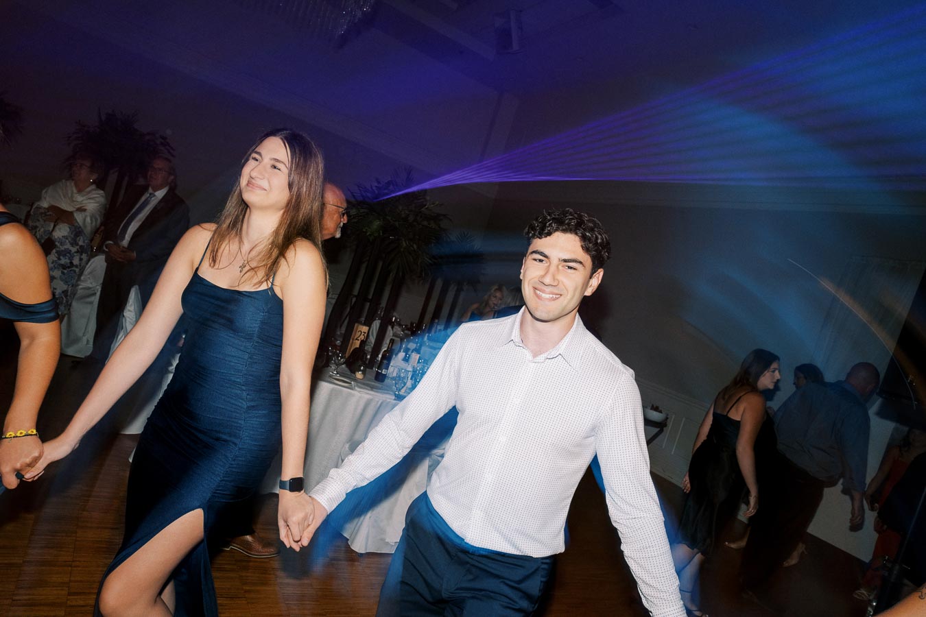 People dancing joyfully at a party with laser lights and a festive atmosphere.