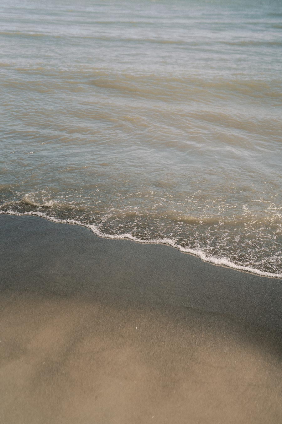 Calm ocean waves gently lapping onto a sandy beach, creating a tranquil coastal scene perfect for relaxation and beach vacations.