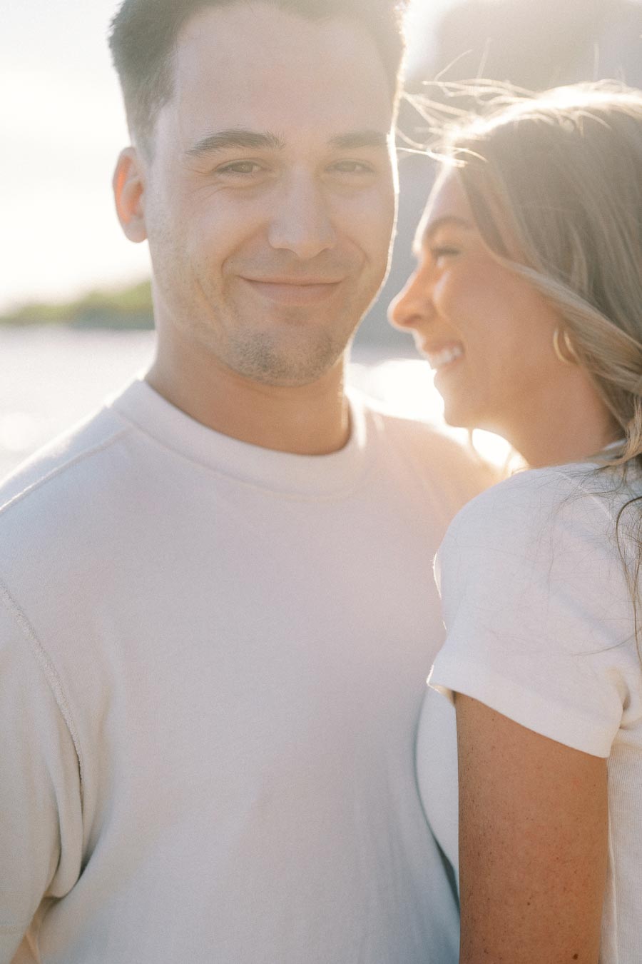 A smiling couple enjoying a sunny day outdoors, with soft sunlight creating a warm, romantic atmosphere.