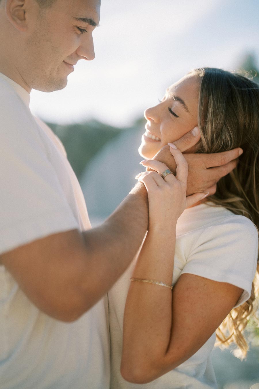 A couple embracing lovingly, gazing into each other’s eyes, bathed in soft, natural sunlight.