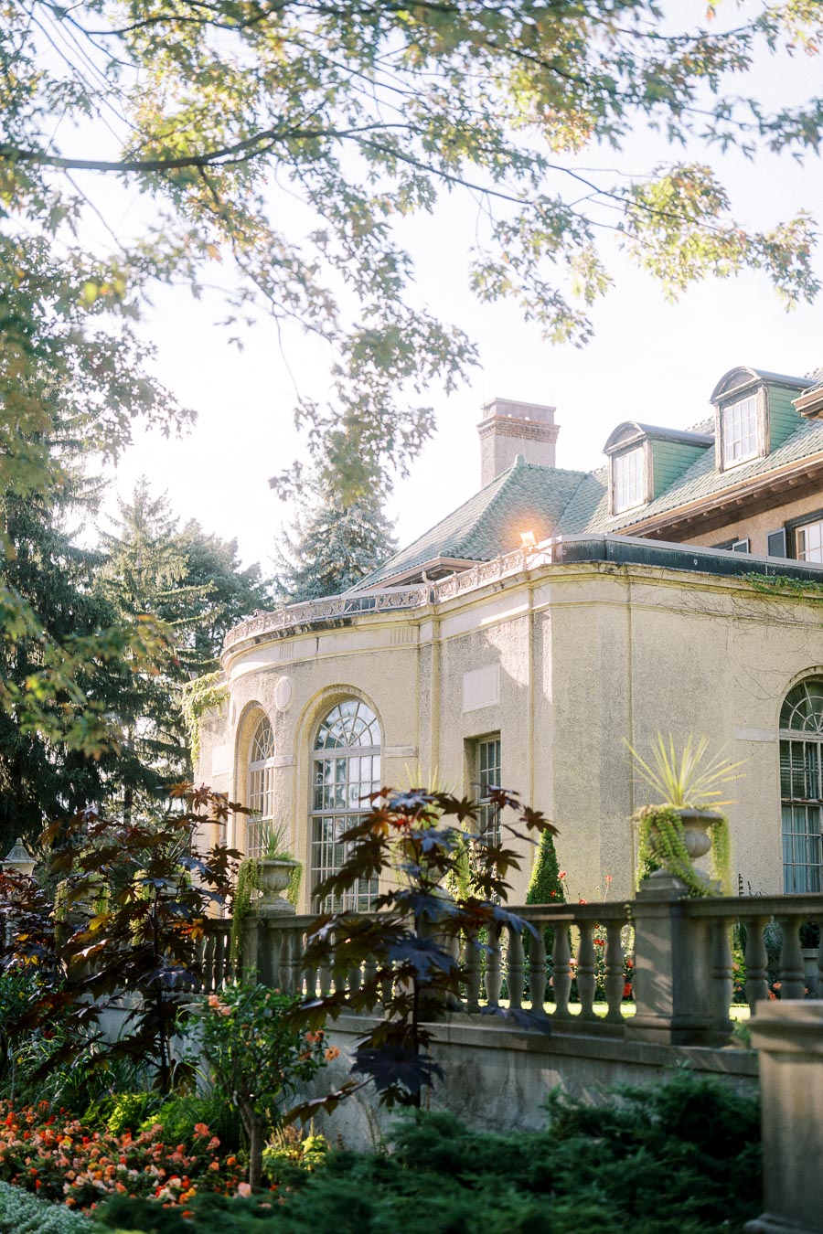 Elegant historic mansion with lush garden and ornate architectural details, bathed in warm sunlight, showcasing classic European design aesthetics.