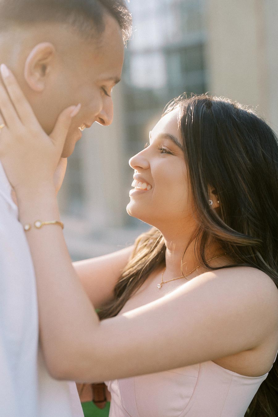 A couple smiling and gazing at each other lovingly in an outdoor setting, capturing a romantic and joyful moment.