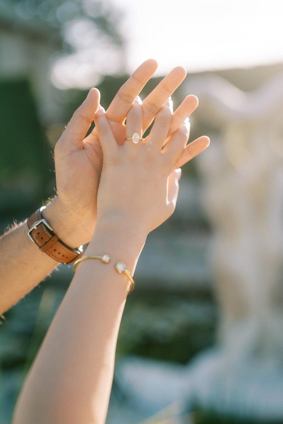 Two hands reaching out, highlighting an elegant engagement ring and bracelet, symbolizing love and commitment.