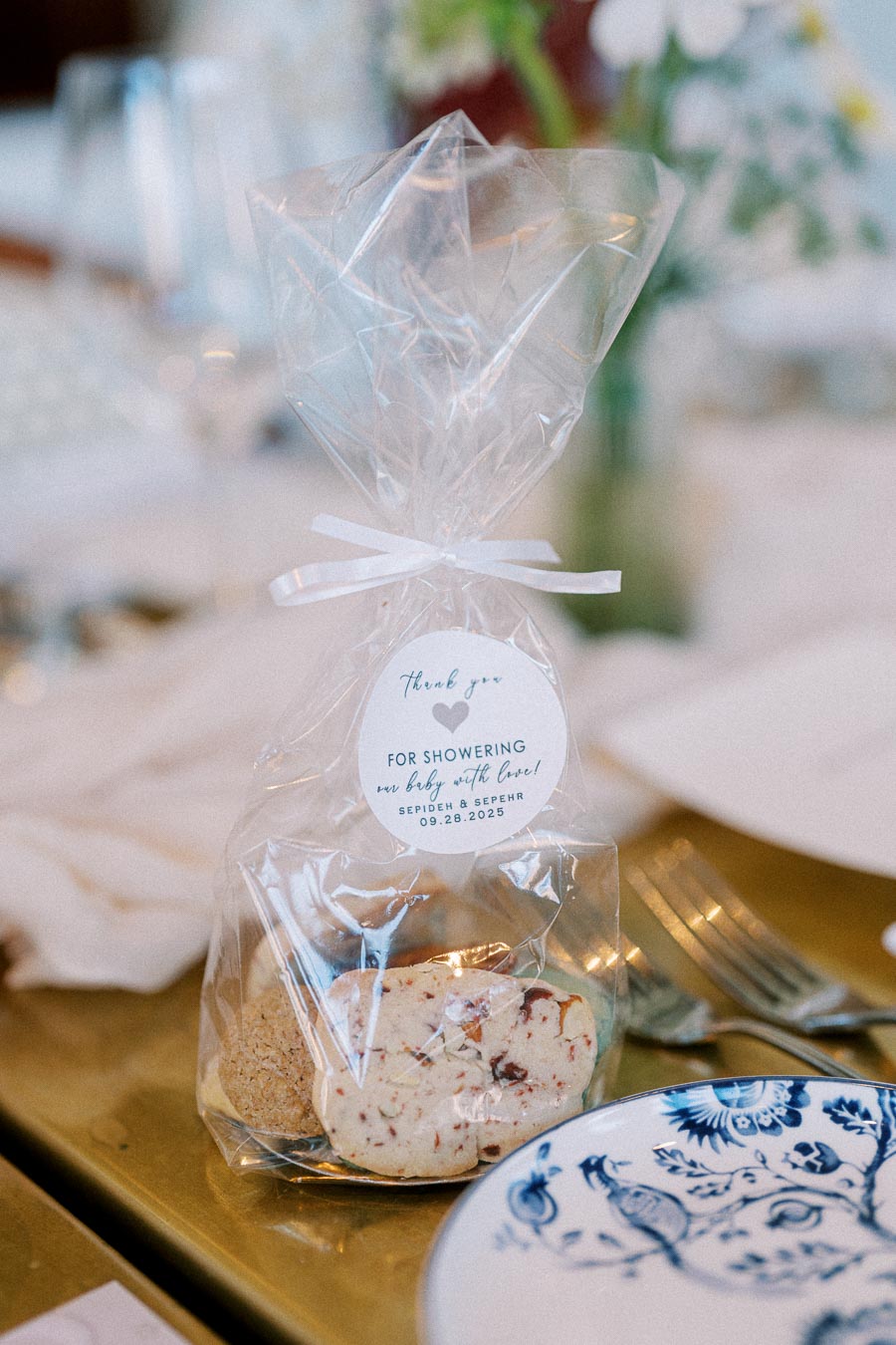 Clear gift bag containing cookies with a thank you tag on a decorated table setting, perfect for baby shower favors.