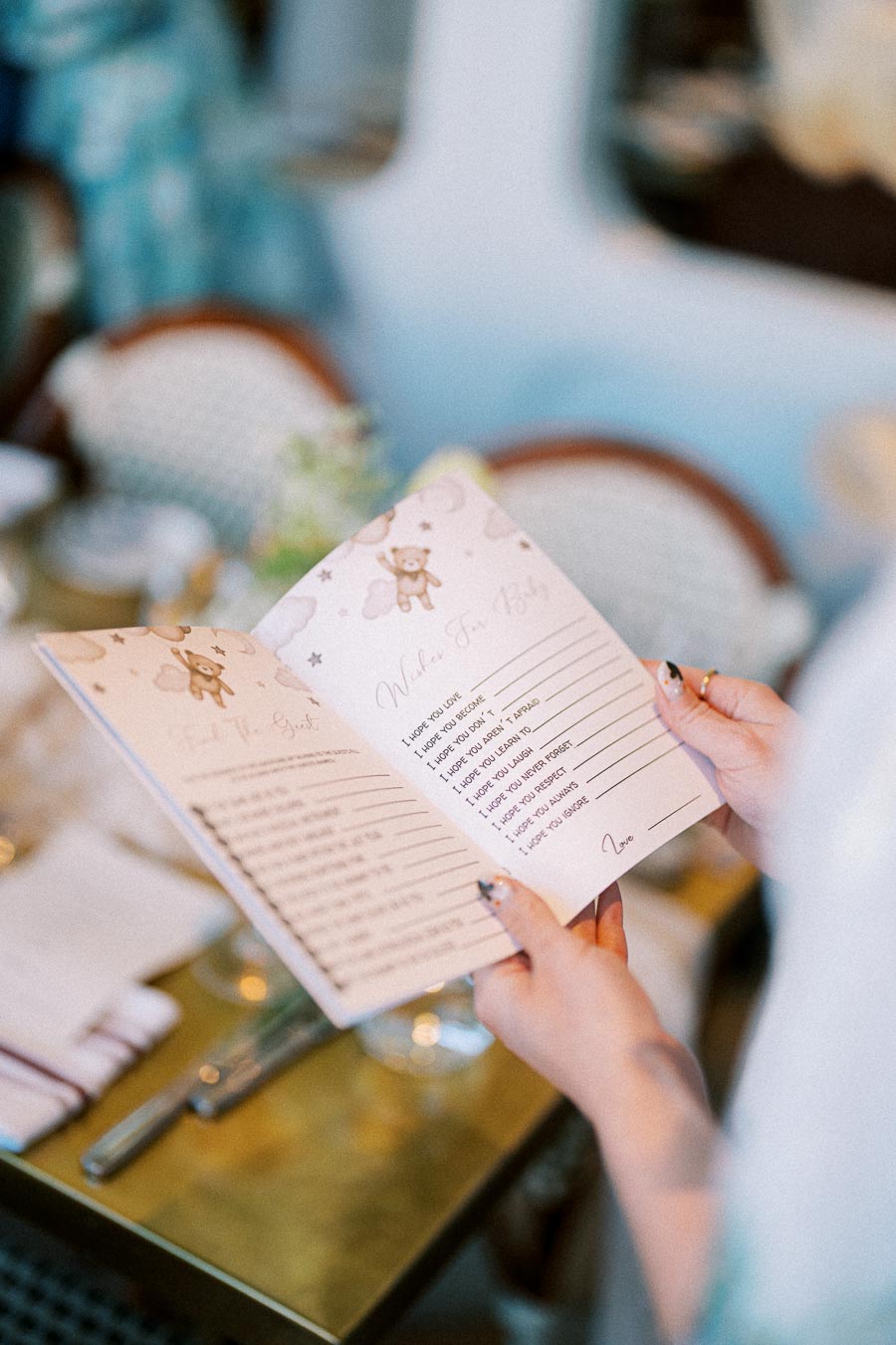 Person holding a baby shower wishes book with prompts like I hope you love and I hope you learn.