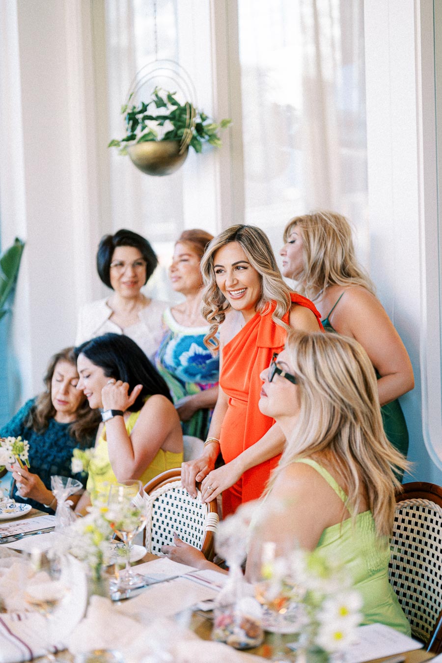 A group of women enjoying a lively gathering, sitting around a beautifully set dining table with elegant decor and flowers, creating a joyful and vibrant atmosphere.