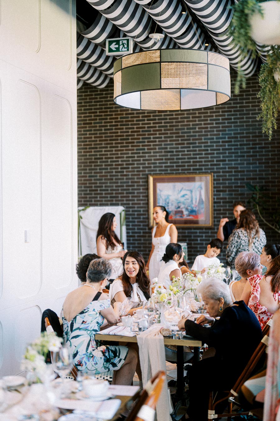 People enjoying a lively gathering in a stylish restaurant setting, with elegant decor and floral table arrangements.