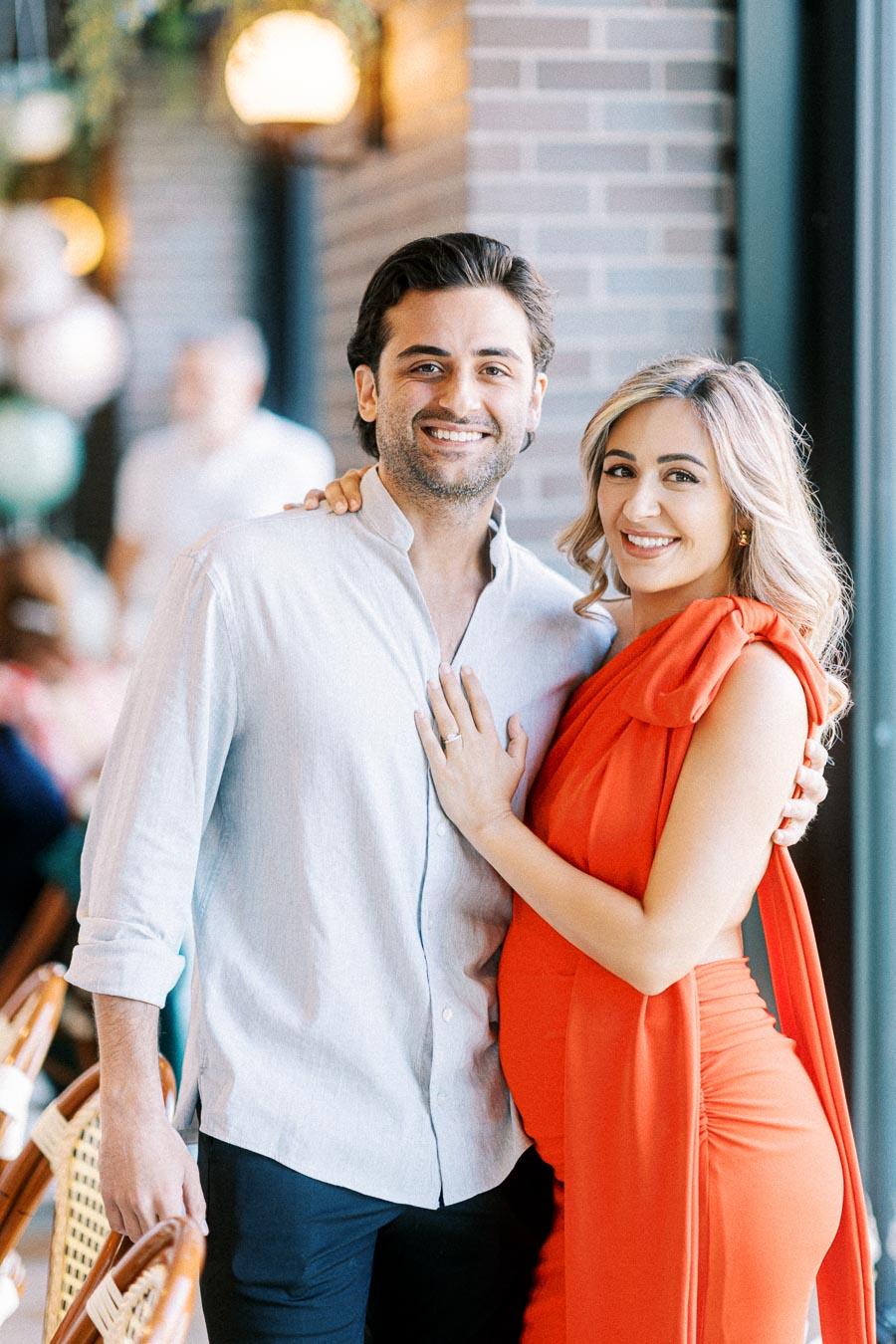 A happy couple embracing in a stylish setting, with the woman wearing a vibrant red dress, showcasing a joyful moment.