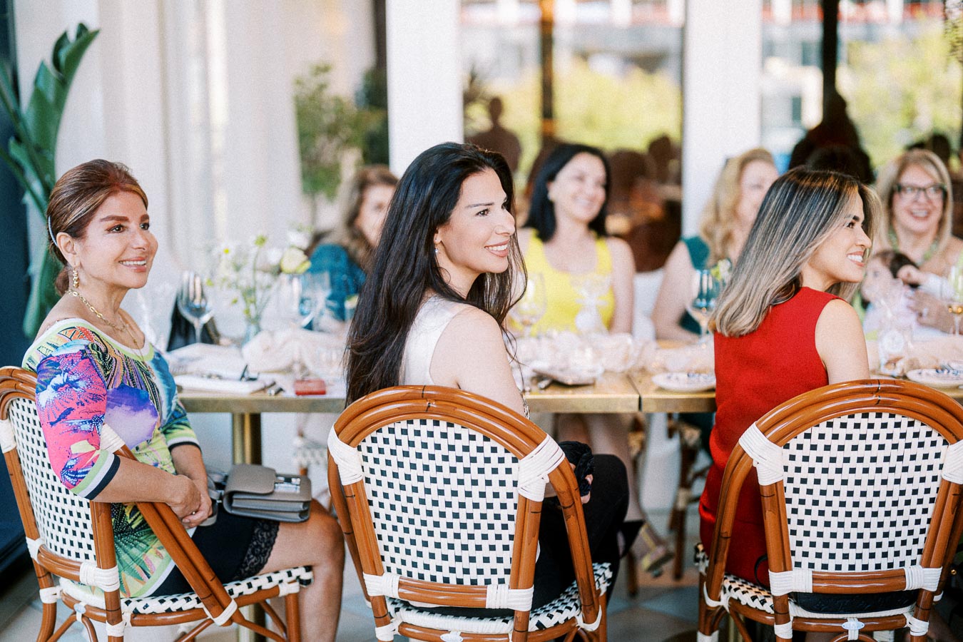 Women enjoying a lively gathering at a stylish restaurant, seated around a table with elegant tableware and floral decorations.