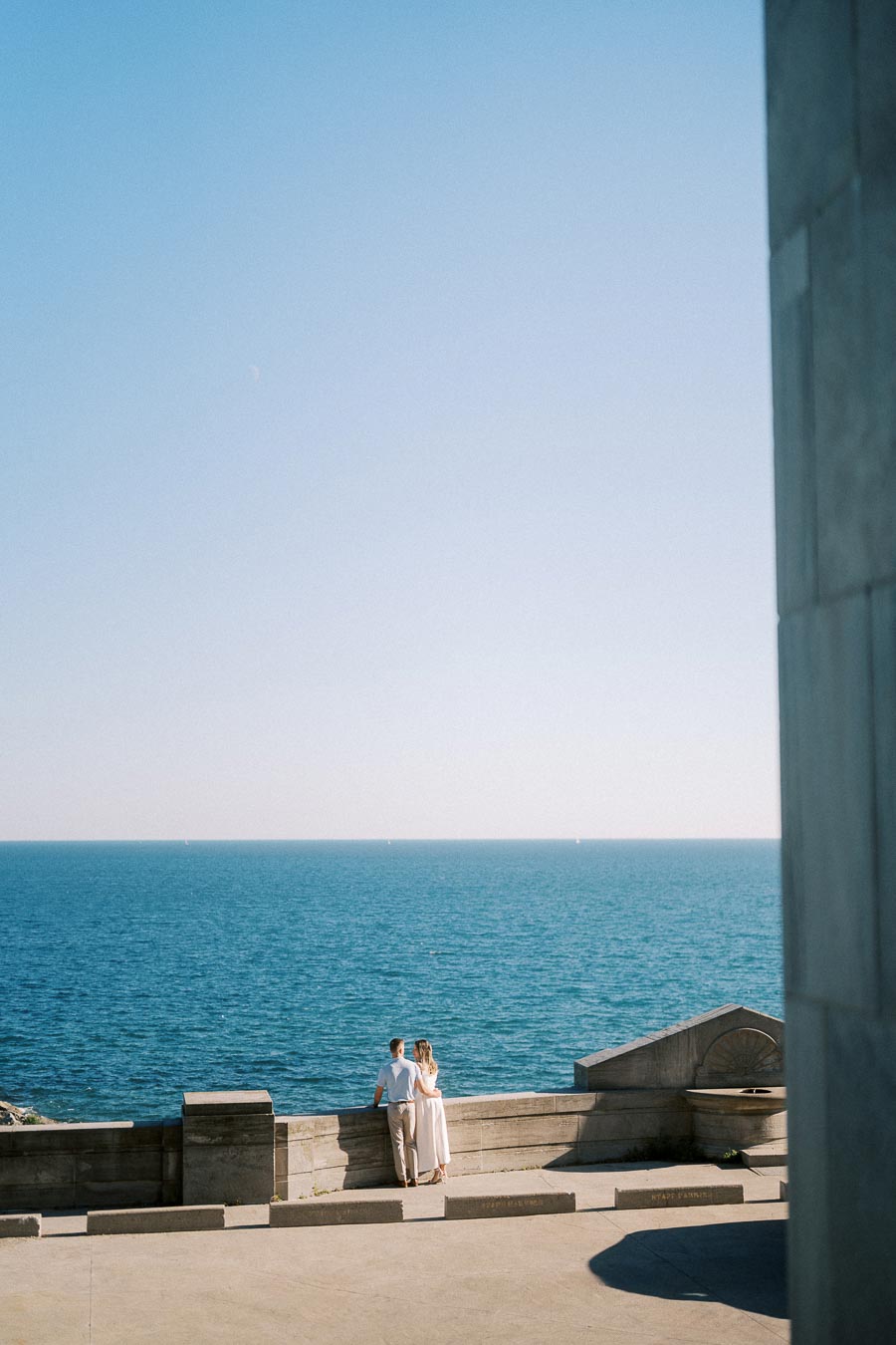 Couple enjoying a scenic ocean view from a concrete promenade on a clear day