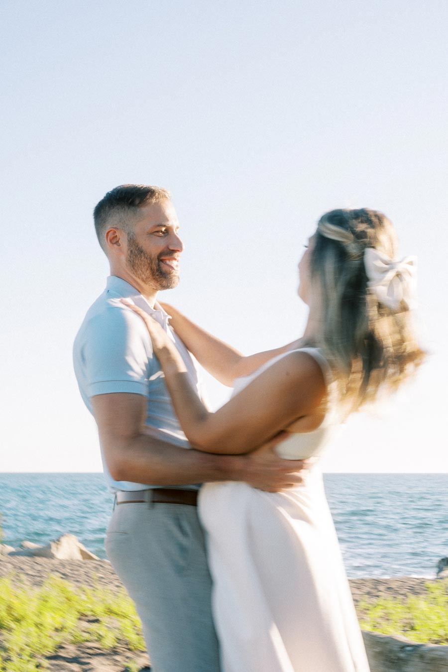 Happy couple embracing on a beach with the ocean in the background, bathed in sunlight.