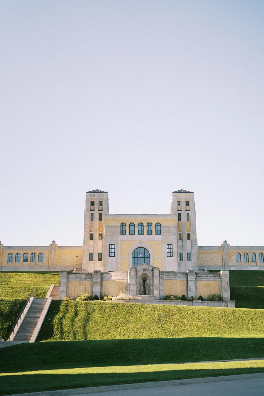 Historic Building with Symmetrical Towers and Green Lawns Under Clear Blue Sky