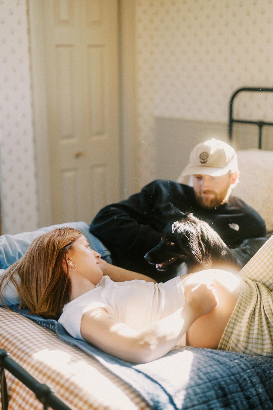 Young couple relaxing on a bed with their dog, enjoying peaceful morning light.