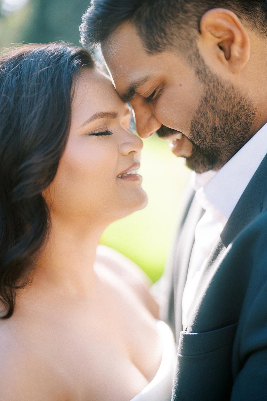 A romantic close-up of a couple gently touching foreheads, with smiles and eyes closed, creating an intimate and serene moment.