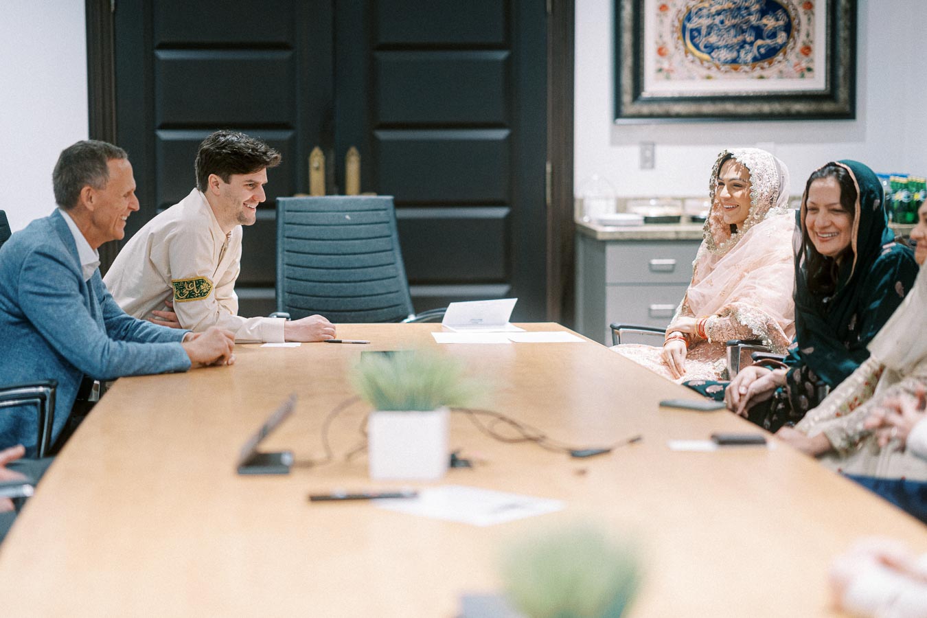 A diverse group of people having a meeting in a conference room, some wearing traditional attire.