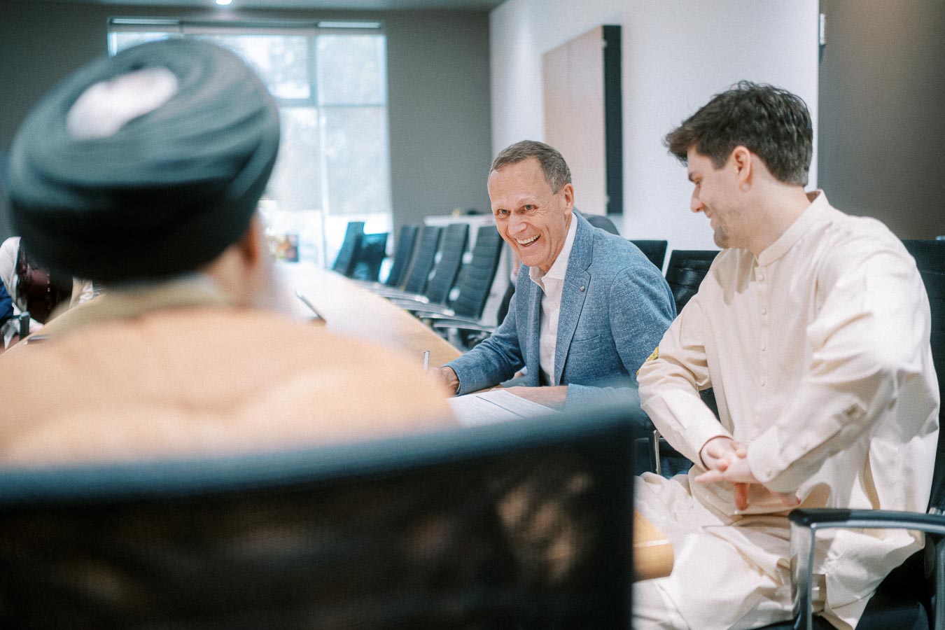 People engaged in a friendly discussion around a conference table, showcasing collaboration and teamwork in a professional setting.