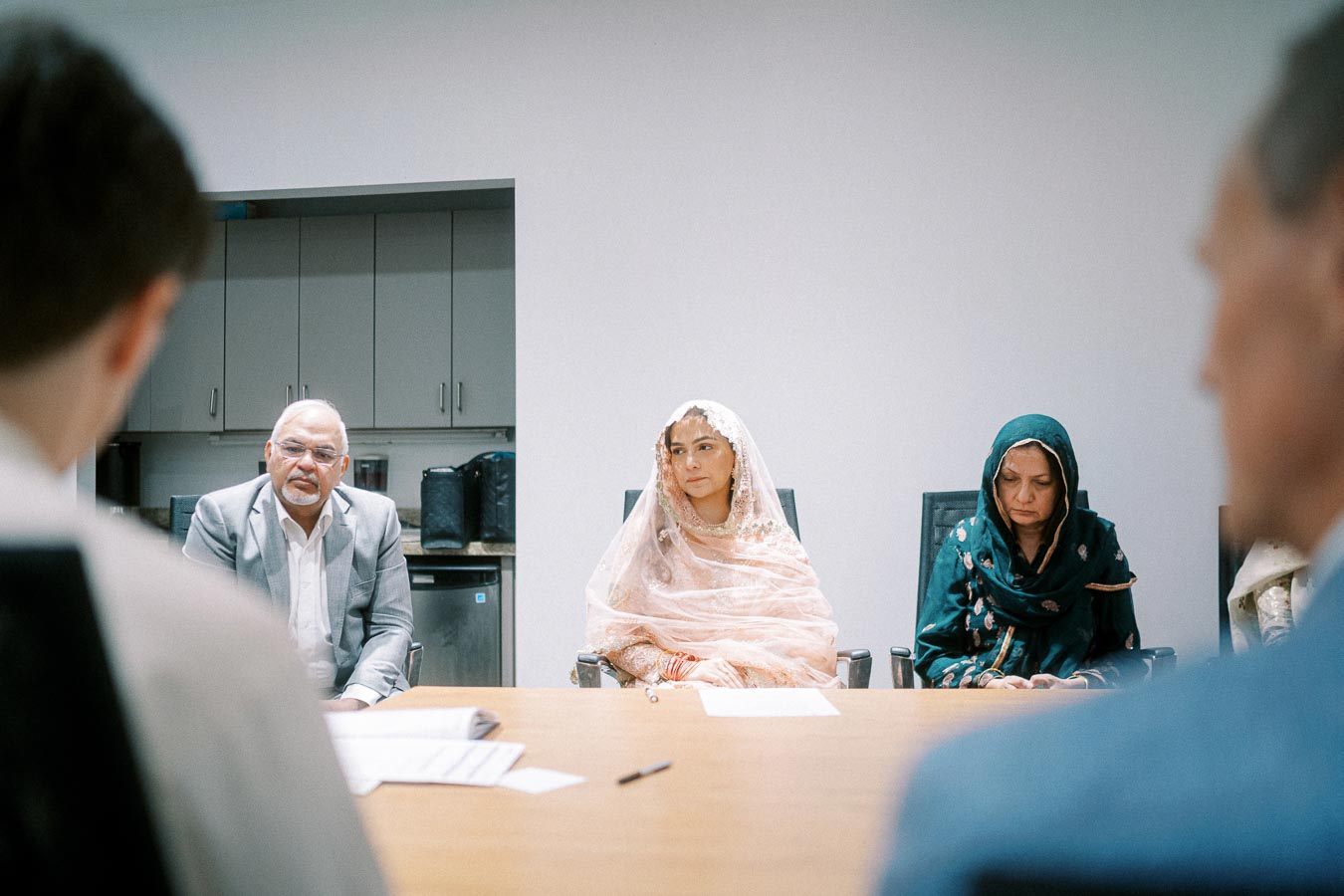 A group of people in traditional attire sitting around a conference table during a formal meeting.