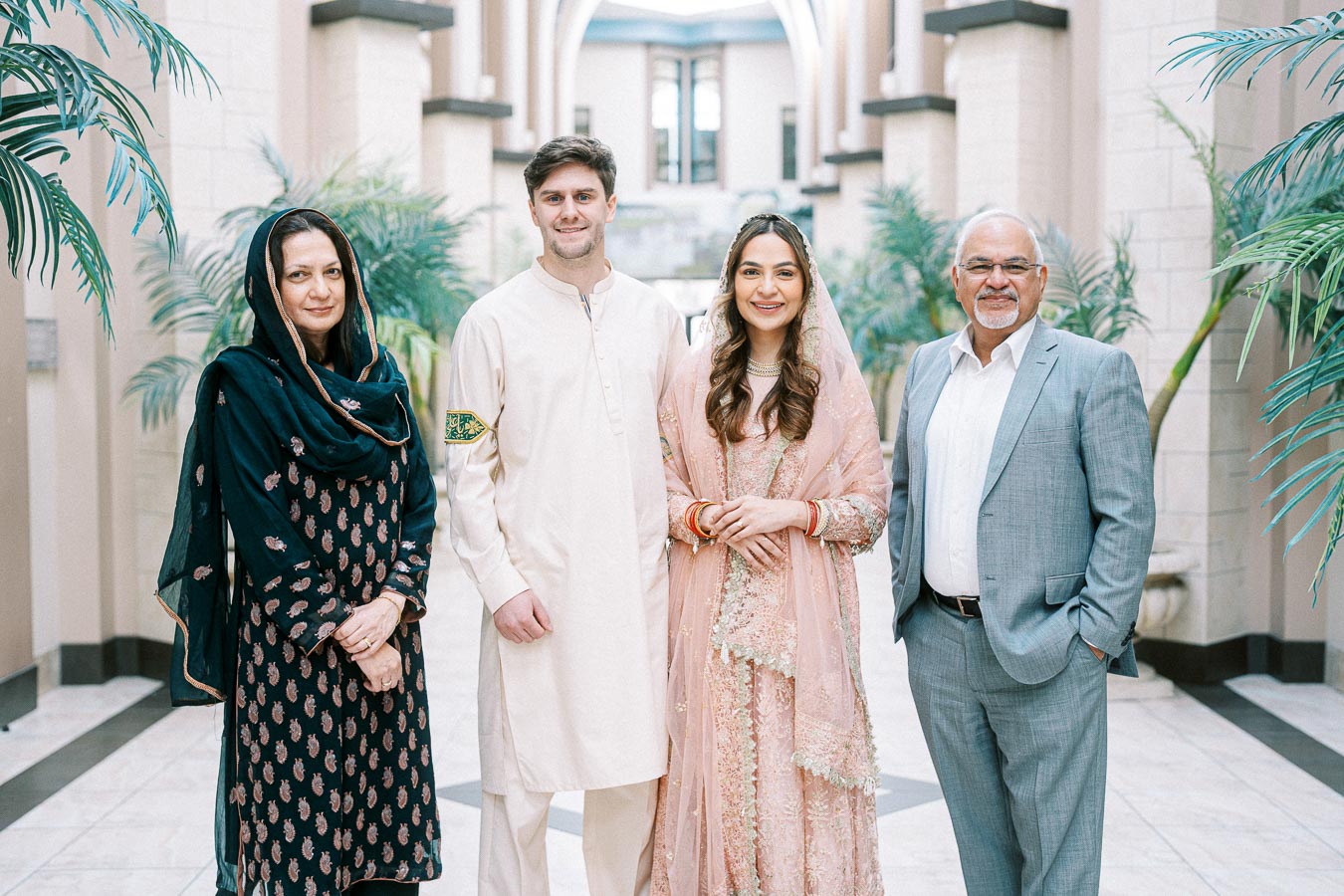 Four people posing in a beautifully decorated indoor setting, dressed in traditional and formal attire, reflecting cultural diversity and elegance.