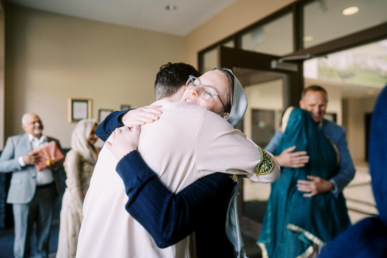 People embracing at a multicultural gathering indoors.