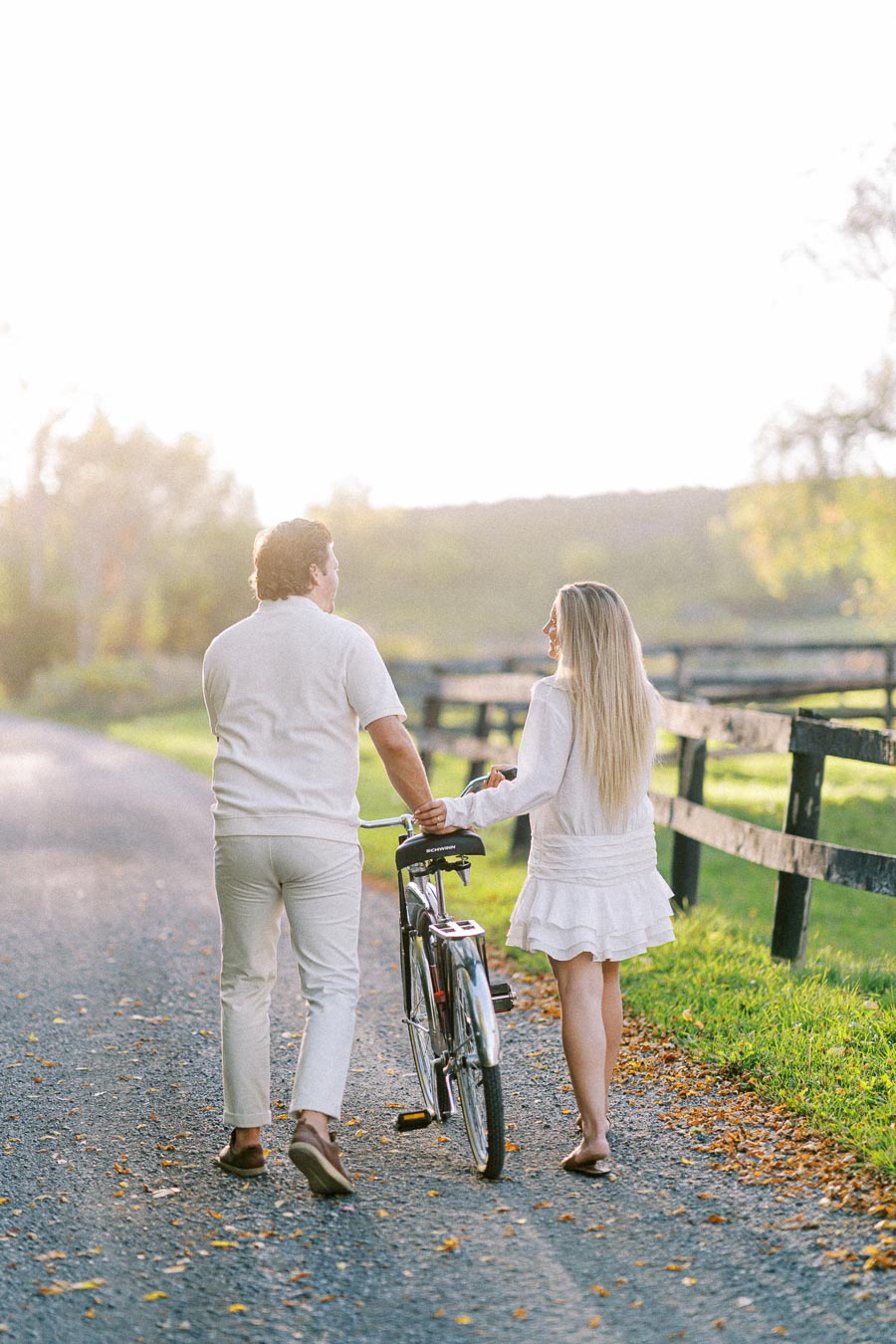 Couple walking with bicycle on scenic country path at sunset