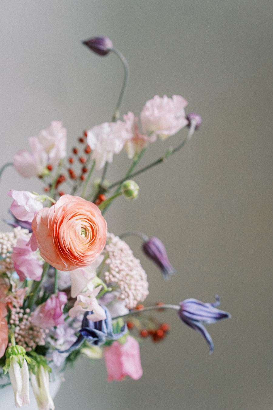 A delicate bouquet featuring pink ranunculus and mixed wildflowers with a soft focus background, showcasing vibrant spring colors and intricate floral details.