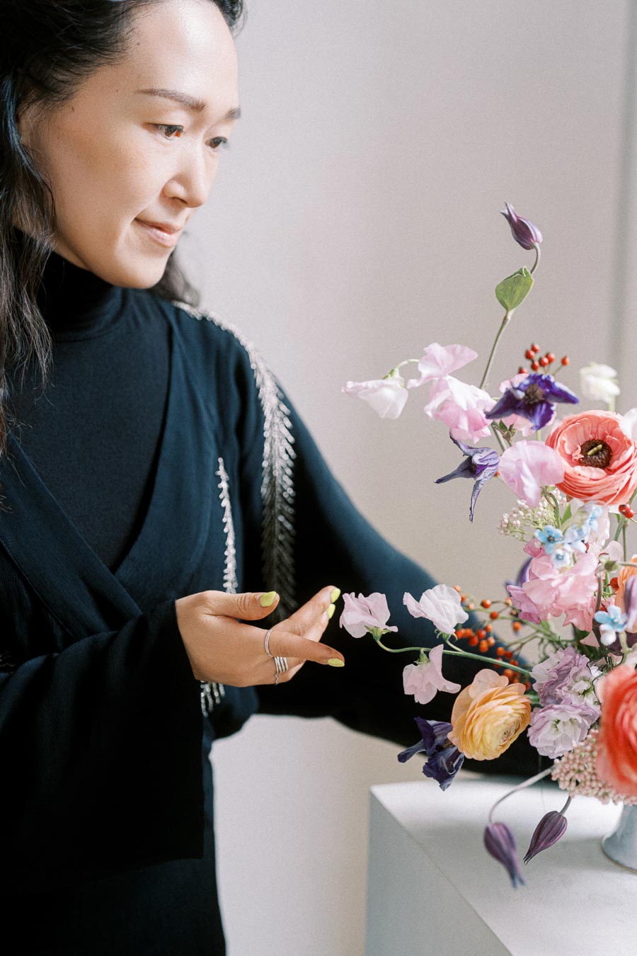 A person arranging a vibrant floral bouquet with pink, purple, and red flowers, showcasing creativity and floral design skills.