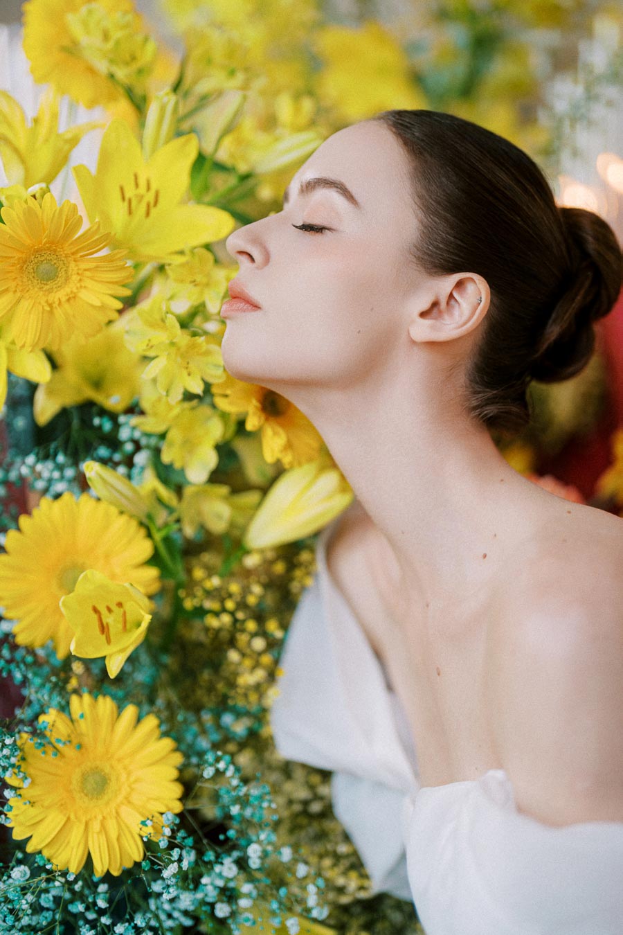 A woman with closed eyes leaning gracefully against a vibrant bouquet of yellow lilies and daisies, with a serene and peaceful expression, suggesting a connection with nature.