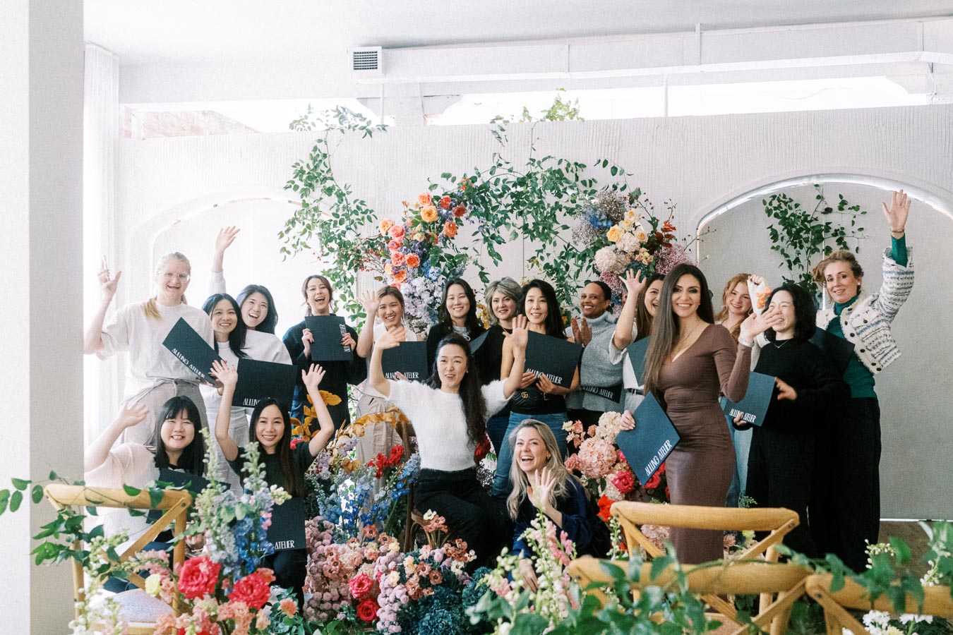 Group of people celebrating at a floral event, holding certificates and waving joyfully.