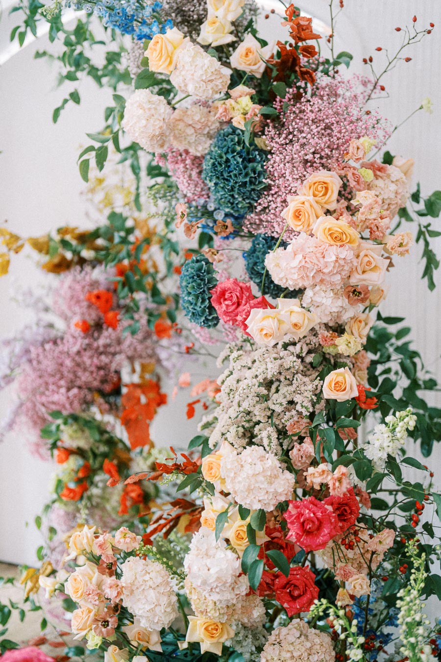 A vibrant floral arrangement featuring a variety of colorful flowers, including roses, hydrangeas, and mixed greenery, creating an elegant and lush display for weddings or special events.