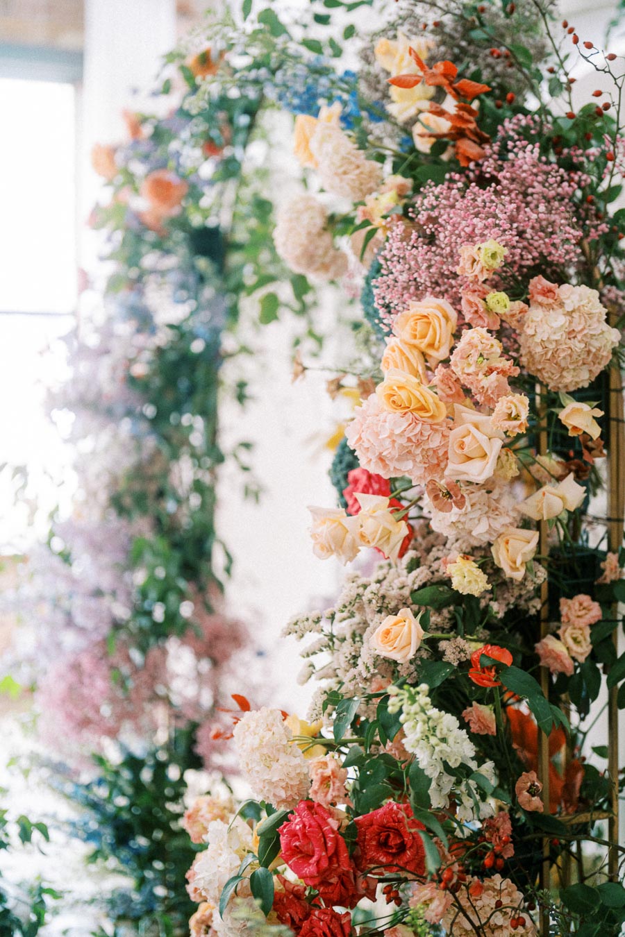 Luxurious floral arch adorned with a vibrant mix of roses, hydrangeas, and assorted greenery, creating a stunning display of color and elegance, perfect for a wedding or garden event.