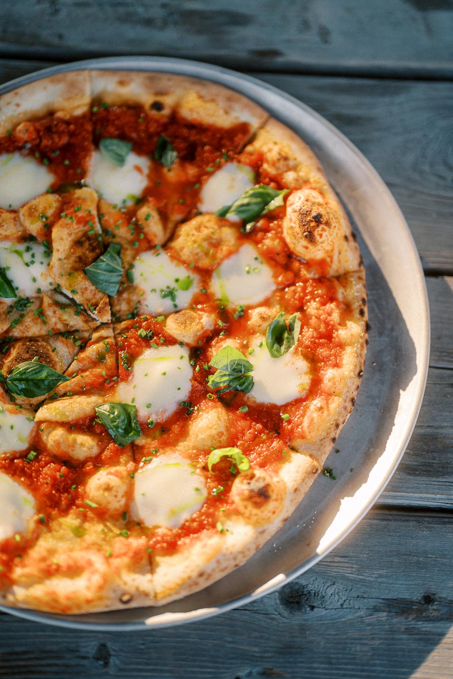 Delicious homemade pizza topped with fresh mozzarella, vibrant tomato sauce, and basil leaves on a rustic wooden table.