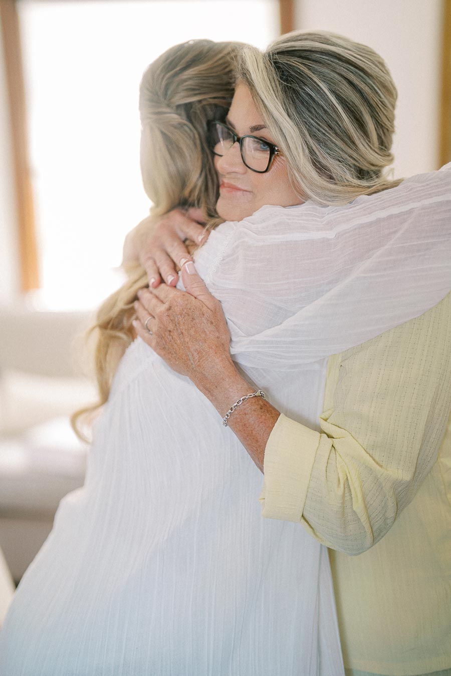 Two people embracing warmly, expressing close connection and support, indoors with soft lighting.