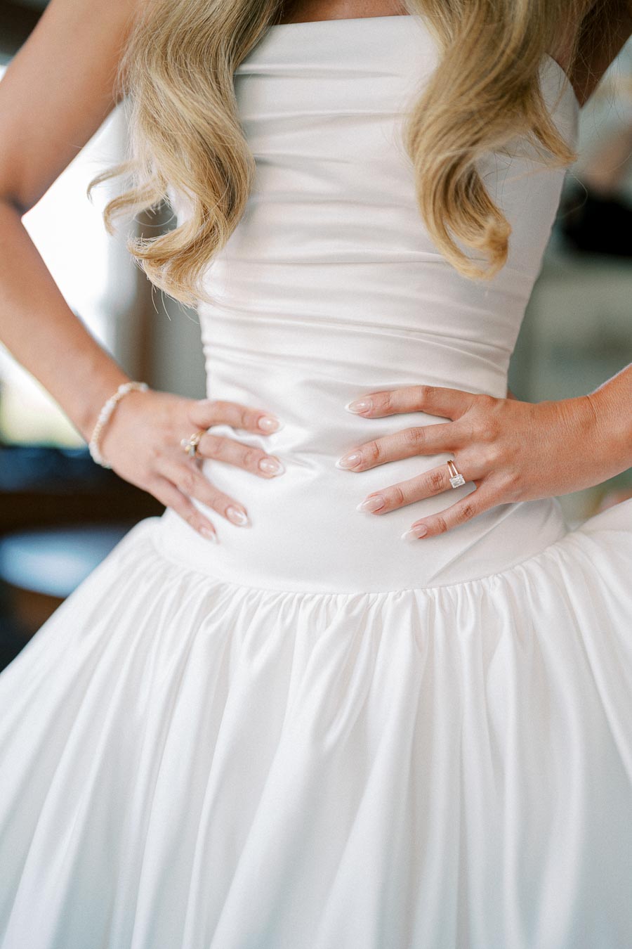 Close-up of a bride in a satin wedding dress showing elegant details including fitted bodice, wavy hair, and wedding ring. Perfect for bridal fashion inspiration.