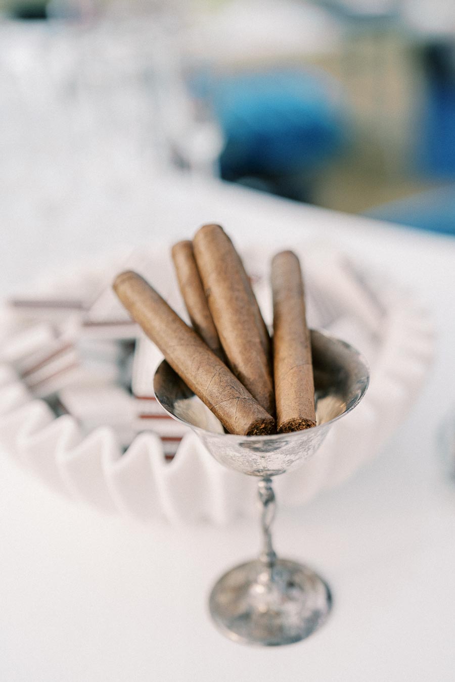 Four cigars elegantly arranged in a silver cup, placed on a white tabletop, offering a sophisticated luxury smoking experience.