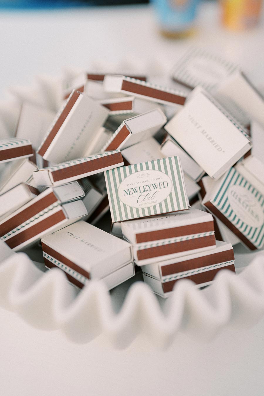 A bowl filled with decorative matchboxes featuring Newlywed Club branding and striped design, ideal for wedding favors or celebration keepsakes.