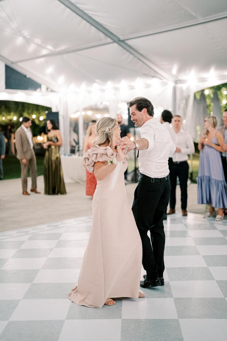 Elegant wedding dance under a white canopy with guests in formal attire observing.