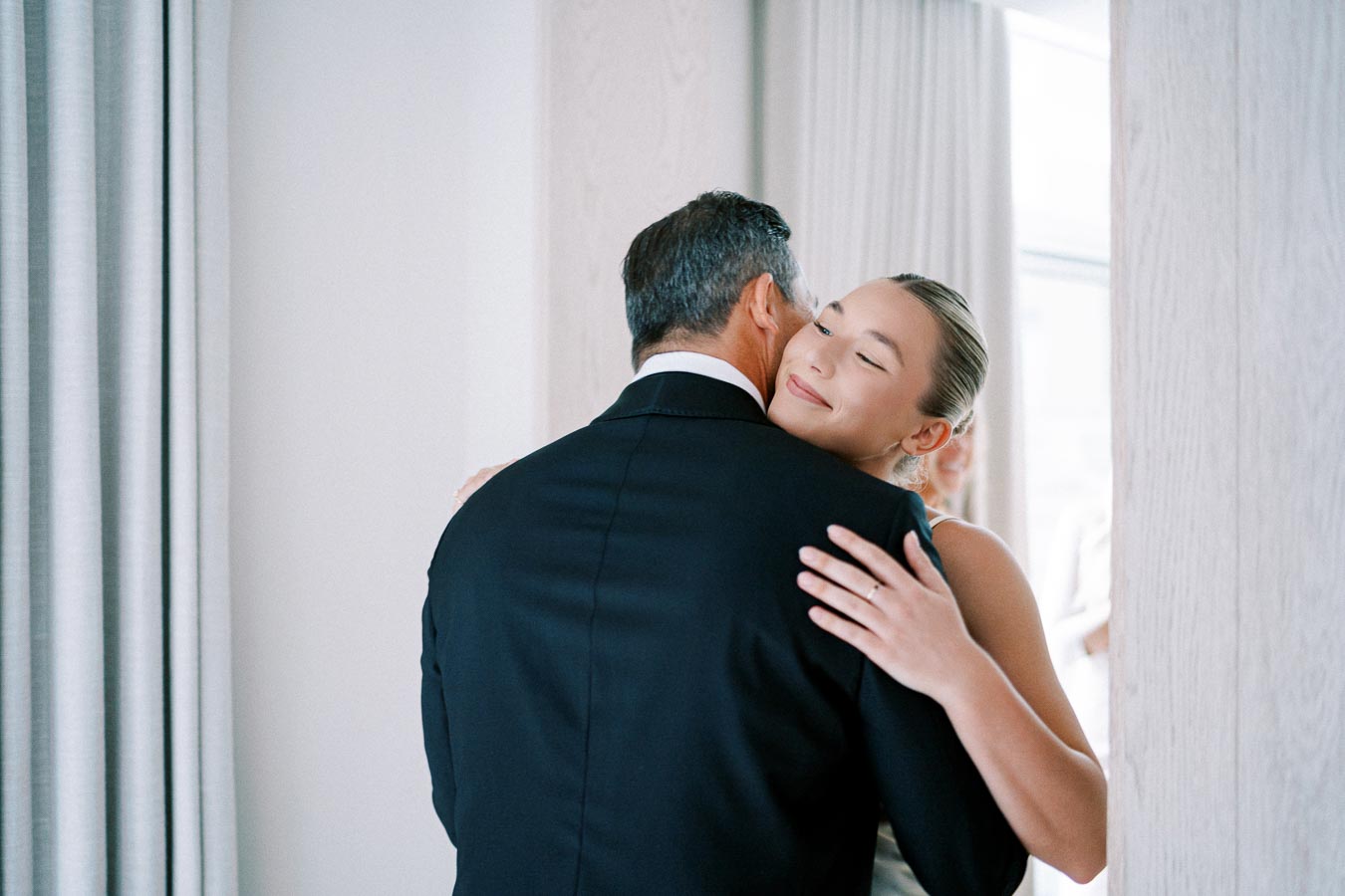Father and bride share an emotional hug before wedding ceremony, expressing love and connection.
