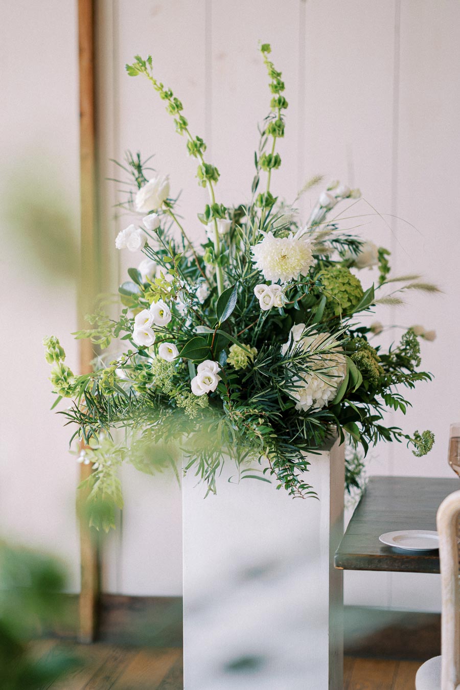 Elegant floral arrangement with white roses and greenery in a modern indoor setting, creating a fresh and natural ambiance.