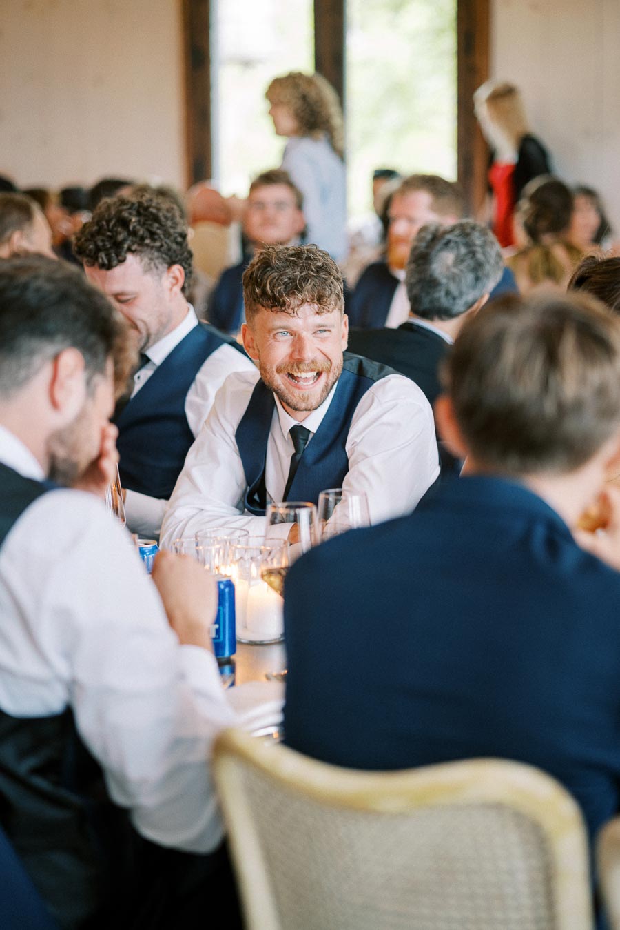 Guests enjoying a lively conversation at a formal event, dressed in suits and ties.