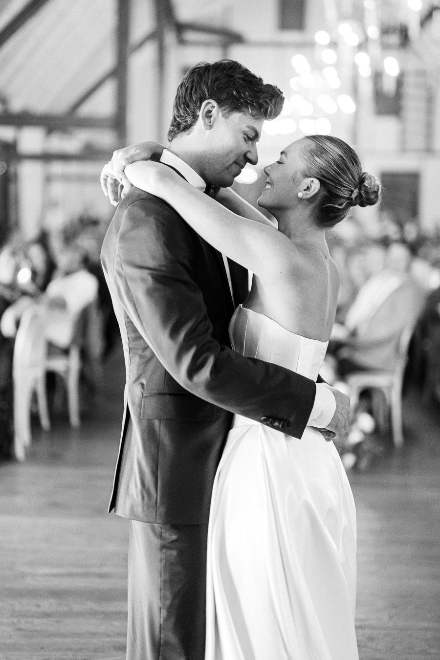 Elegant bride and groom sharing a romantic first dance in a beautifully lit wedding venue, capturing a timeless and joyful moment.