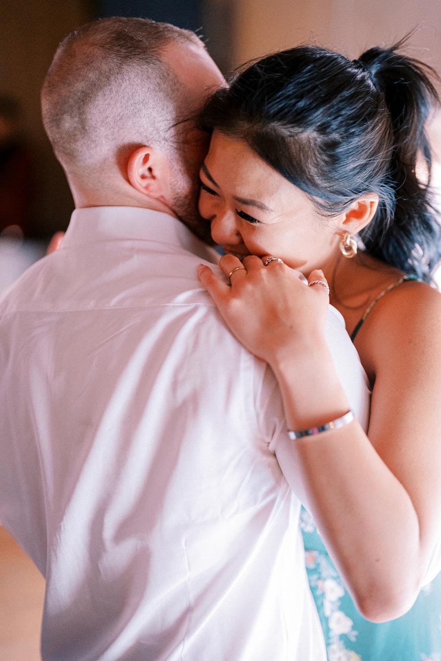 A couple embracing and smiling while dancing at a wedding reception, capturing a joyful and intimate moment.