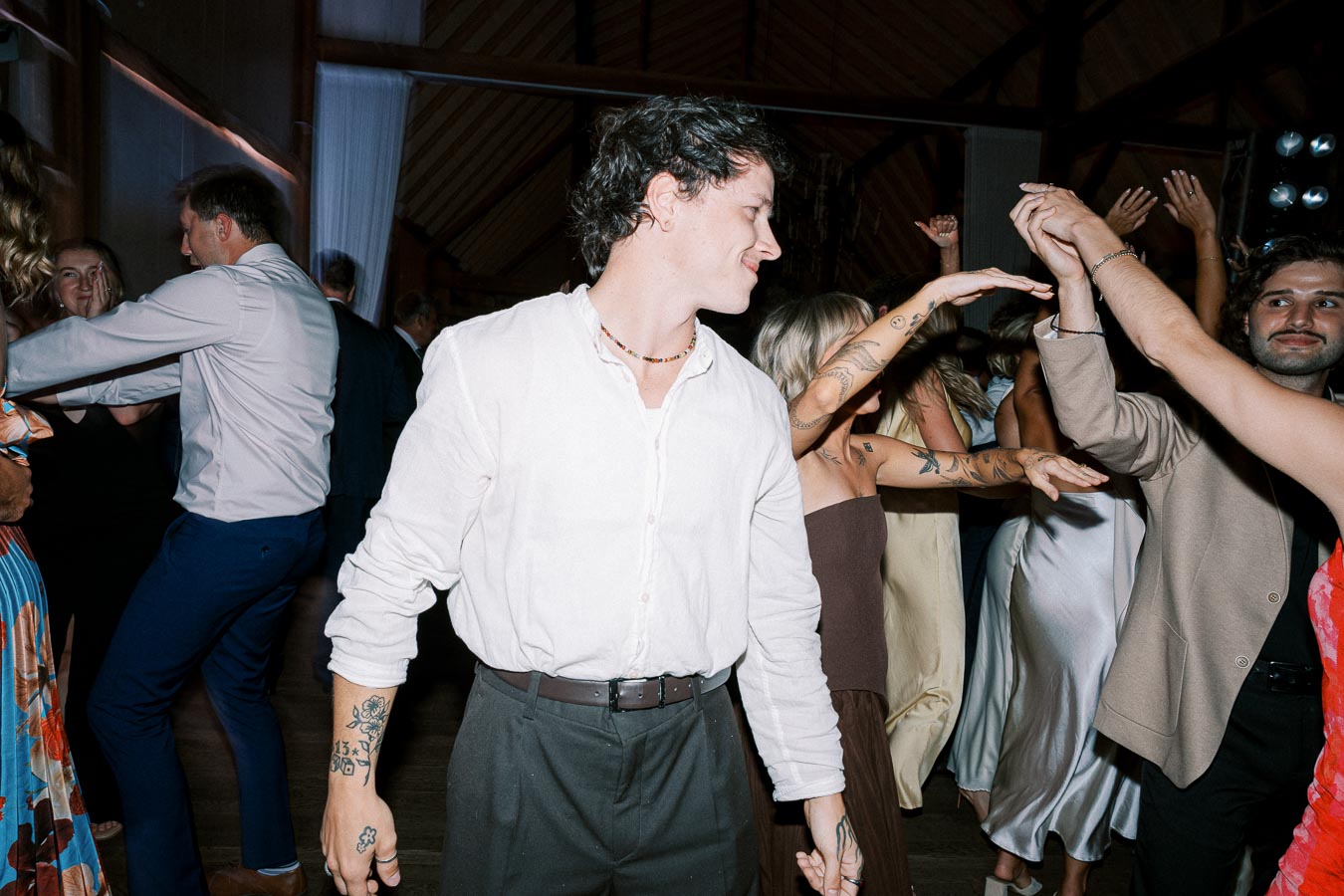 People dancing joyfully at a lively party, featuring a man in a white shirt in the foreground.