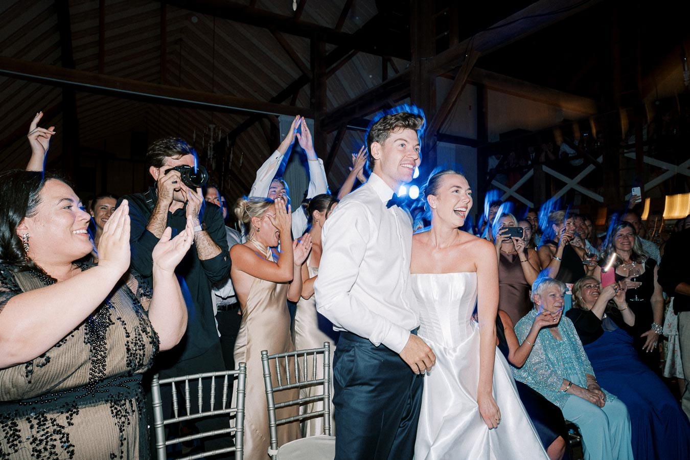 A joyous wedding celebration with a bride and groom surrounded by applauding guests, capturing a heartfelt moment of happiness.