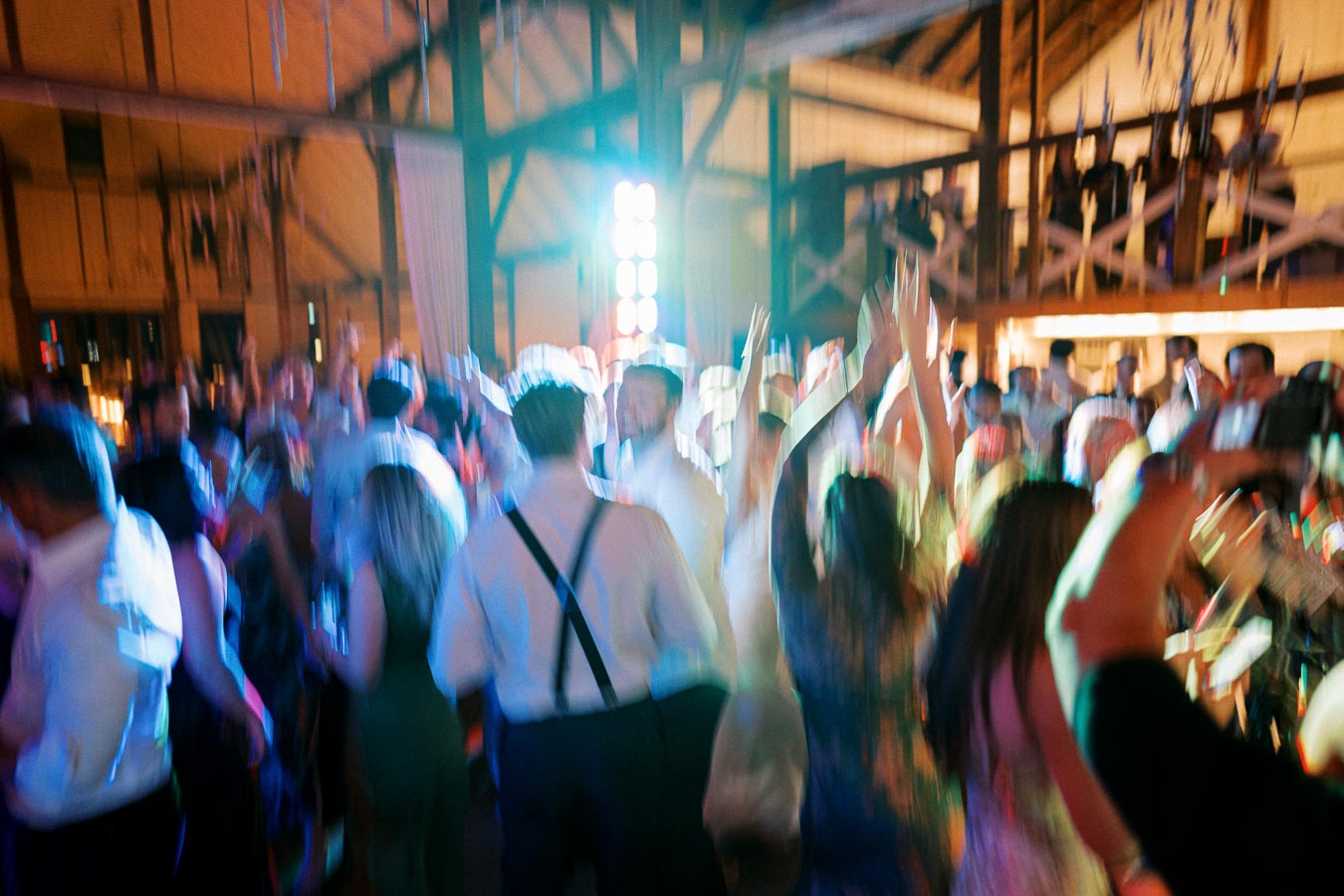 Blurred image of a lively indoor party with people dancing under colorful lights, creating a vibrant and energetic atmosphere.