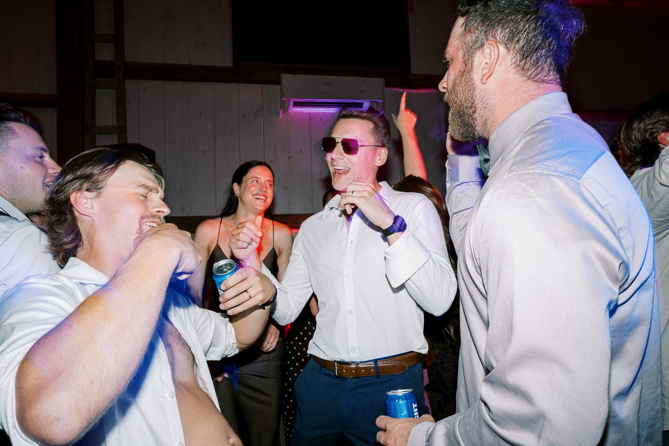 Group of friends enjoying a lively party, dancing and socializing, with vibrant lighting and drinks in hand, capturing a fun and energetic celebration atmosphere.