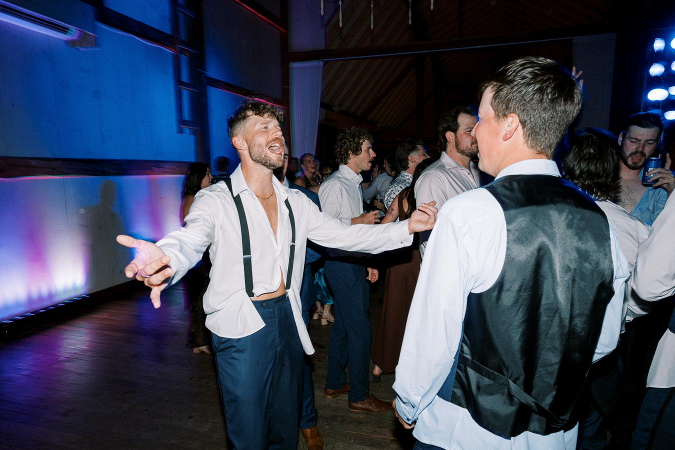 Group of people dancing and celebrating at a party with vibrant blue and pink lighting