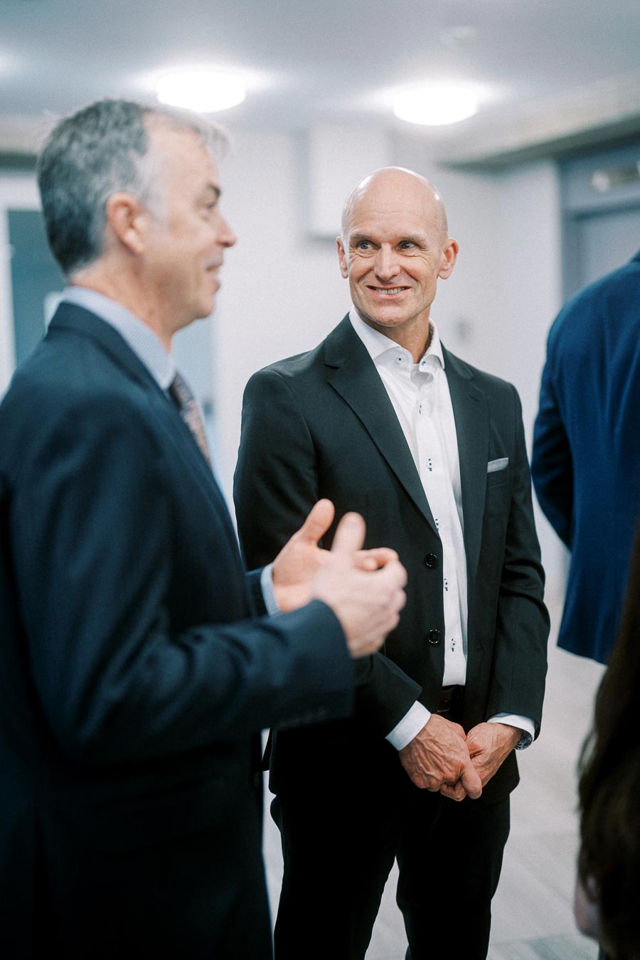 Two businessmen in suits engaging in conversation at a formal networking event, highlighting professional interaction and communication.