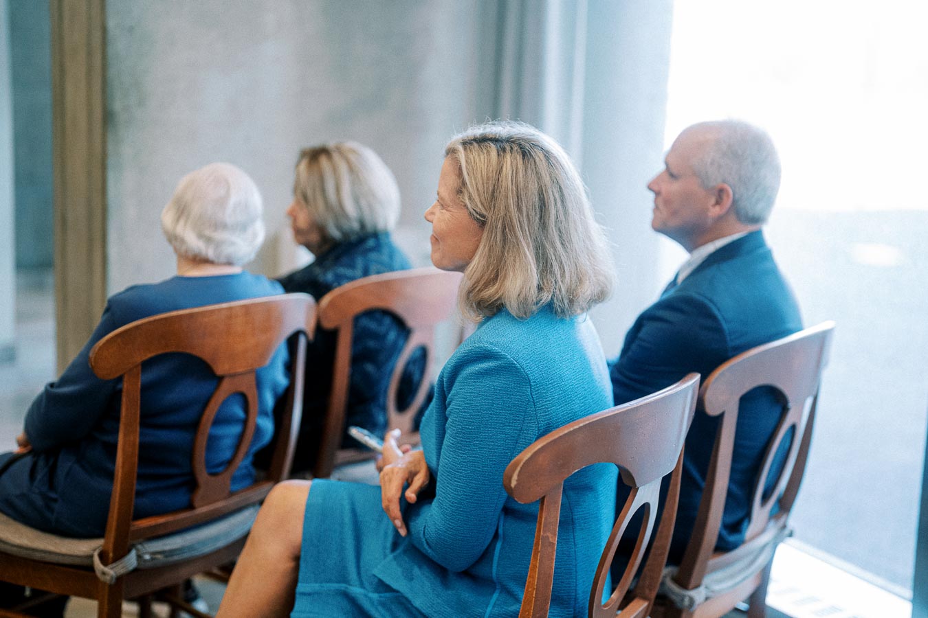 Four people sitting attentively in a formal setting, dressed in blue attire, suggesting a professional or formal event.